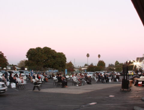 People gathered outdoors in a parking lot during sunset.