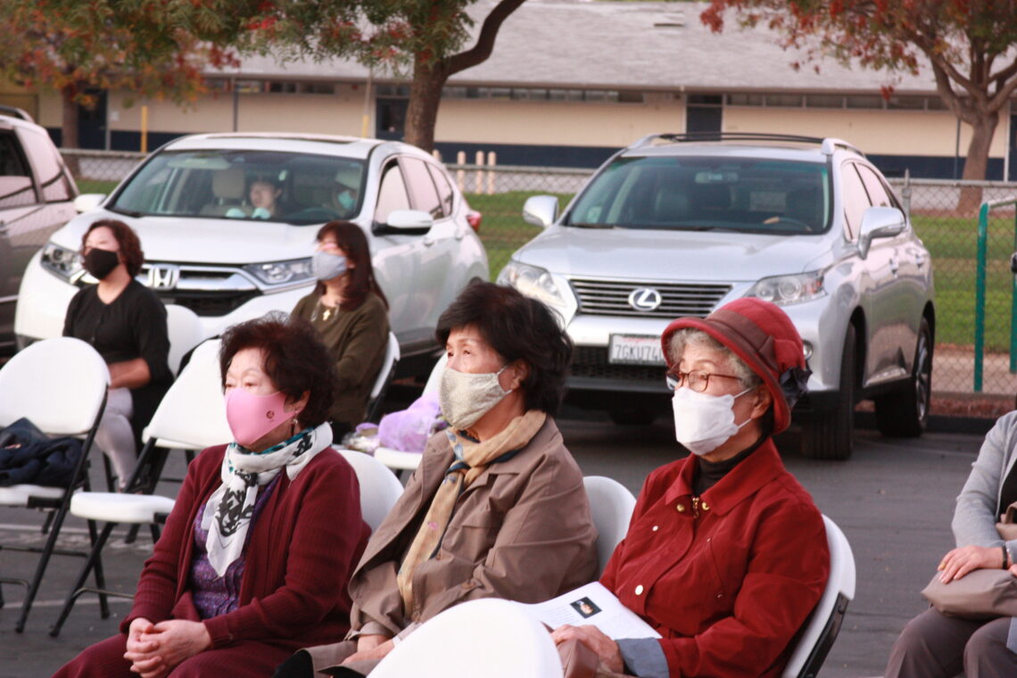 Group of elderly women wearing masks sitting outdoors.