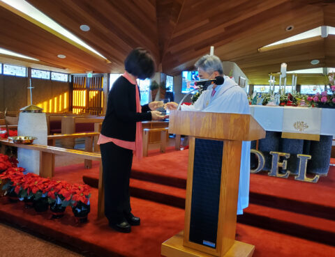 Two women exchanging a handshake in a church setting.