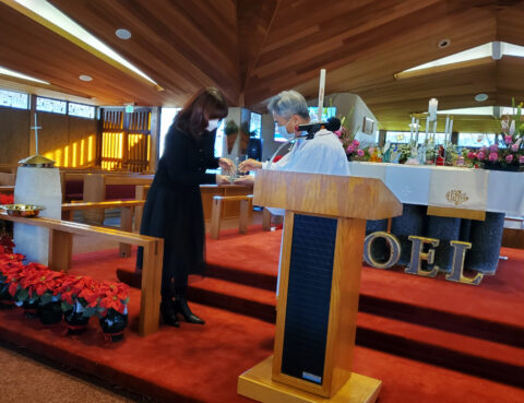 People gathered at a podium inside a wooden chapel.