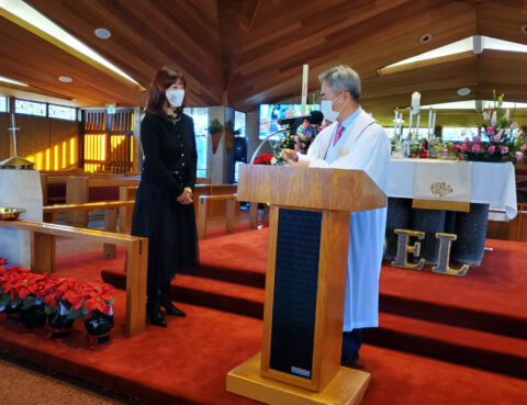 A woman in black speaks with a man at a church podium.
