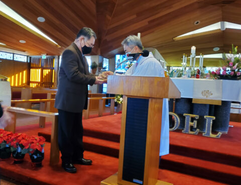 Two men in a church performing a ceremony at the altar.