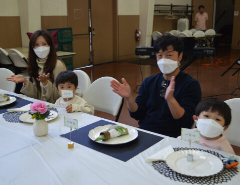 Family enjoying a meal together, wearing masks indoors.