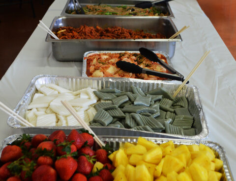 A buffet spread with fruits, wrapped leaves, and various dishes.