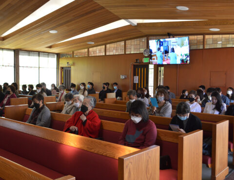 Congregation seated in a church sanctuary wearing masks during a service.