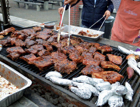 Grilled meat sizzling on a large outdoor barbecue grill.