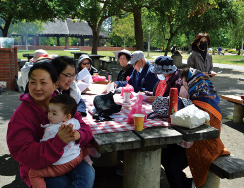 Family picnic with multiple generations enjoying outdoors together.