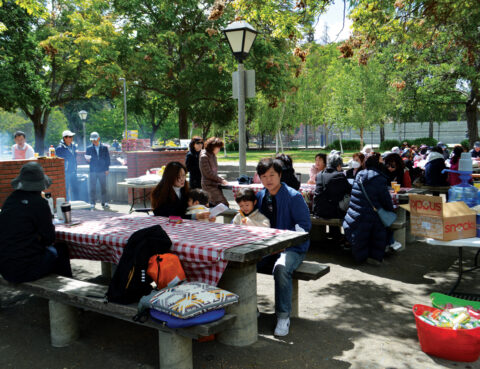 People enjoying a sunny day at a picnic table in a park.