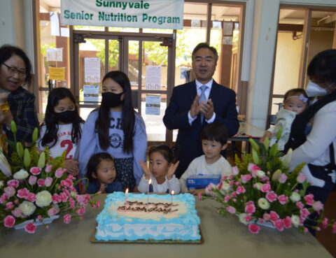 Children and an adult celebrating with a cake at a nutrition program event.