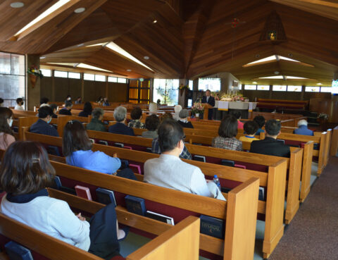 People attending a church service inside a wooden chapel.
