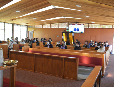 A church congregation during a service with a speaker at the pulpit.