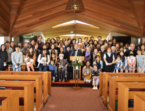 Large group photo inside a church, with diverse attendees and a wooden ceiling.