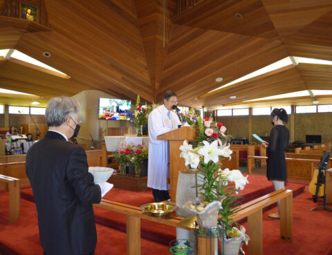 A priest conducts a religious ceremony inside a wooden church with attendees.
