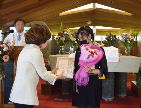 A woman receives an award and flowers in a formal ceremony.