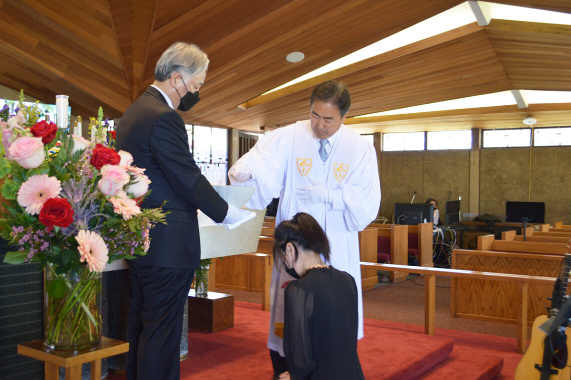 A man and woman participating in a formal ceremony in a church setting.