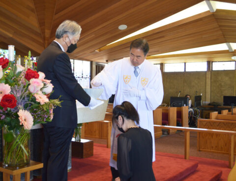 A man and woman participating in a formal ceremony in a church setting.