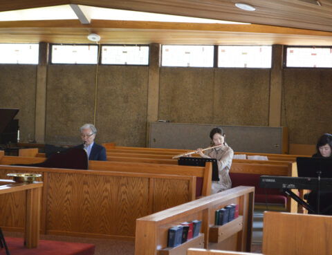 Two elderly people sitting apart on wooden benches in a quiet room.