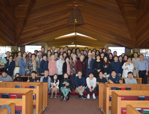 Large group gathered inside a wooden chapel posing for a photo.