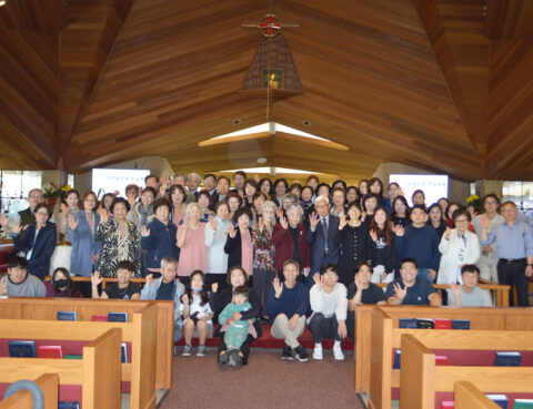 Large group photo inside a wooden church with people smiling.