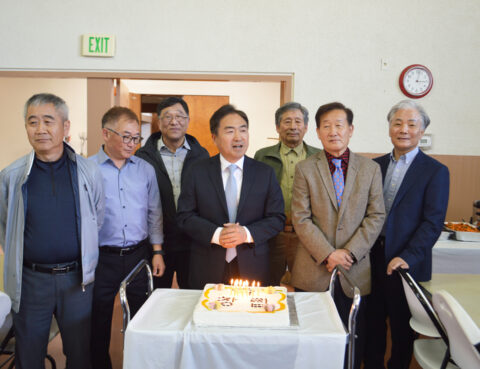 Group of men celebrating with a cake indoors.