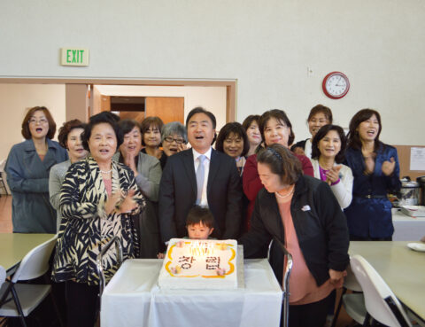 A group of people gathered around a cake celebrating an event.