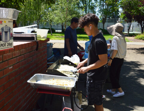 People serving food outdoors at a community event.