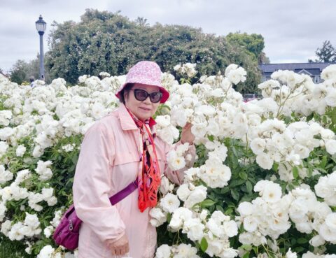 Woman in pink outfit posing with white flowers outdoors.