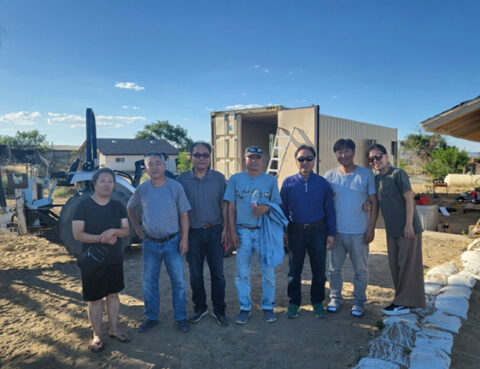 Group of seven people standing outdoors on a sunny day.
