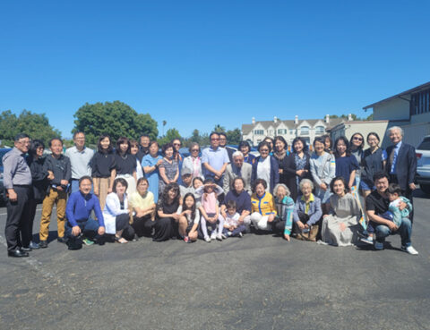 Large group photo taken outdoors on a sunny day with clear blue sky.
