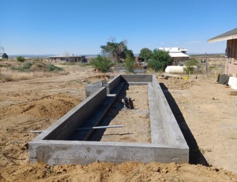 Concrete foundation for a structure being built in a sandy area.