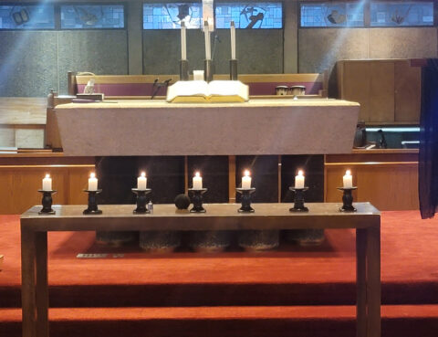 A church altar with lit candles and an open Bible.
