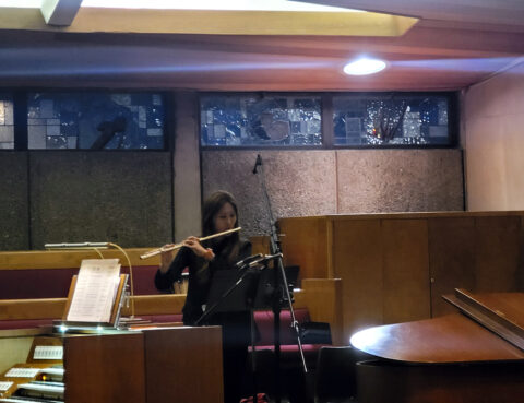 Musician playing flute in a cozy indoor setting.