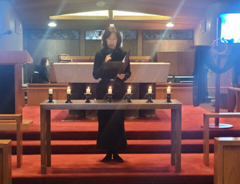 Person standing behind a wooden altar in a church.