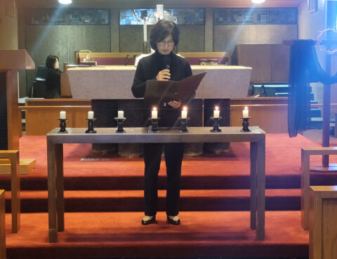 Person lighting candles on a wooden altar in a church.