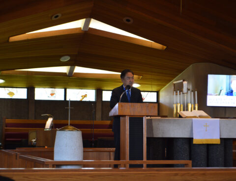 Man delivering a speech from a podium inside a modern church.