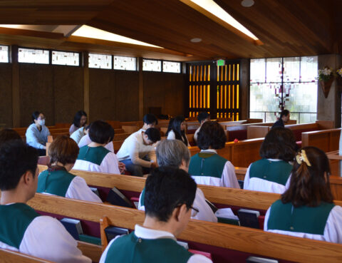 People attending a church service, sitting in pews facing the altar.
