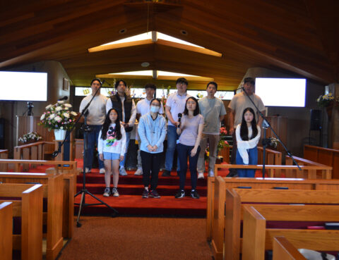 Group of people posing inside a church with wooden pews.