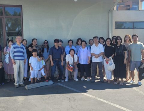 A large group of people posing outdoors on a sunny day.