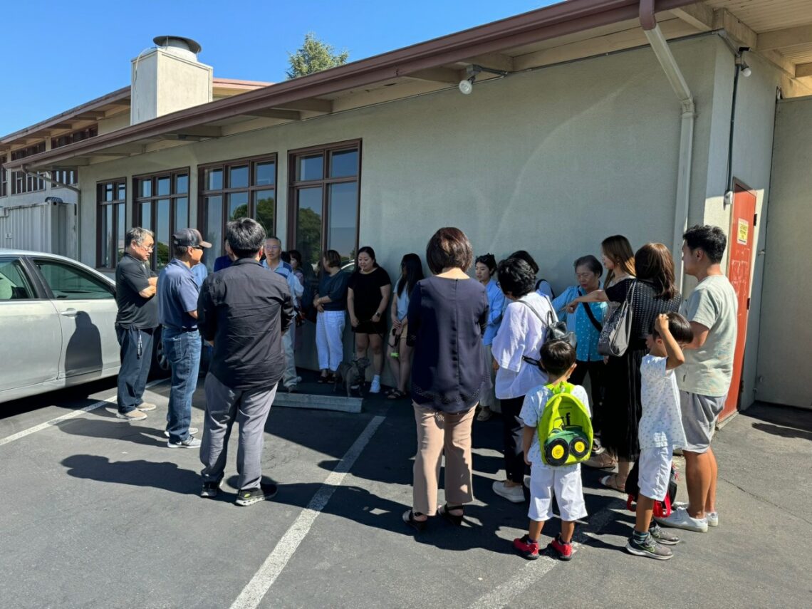 A group of people gathered outside a modern building on a sunny day.