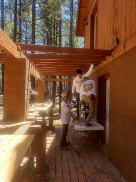 Construction workers building a wooden structure outdoors.